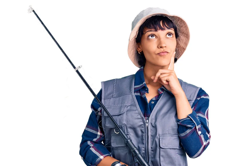 Young brunette woman with short hair in fishing gear, hand on chin, deep in thought.